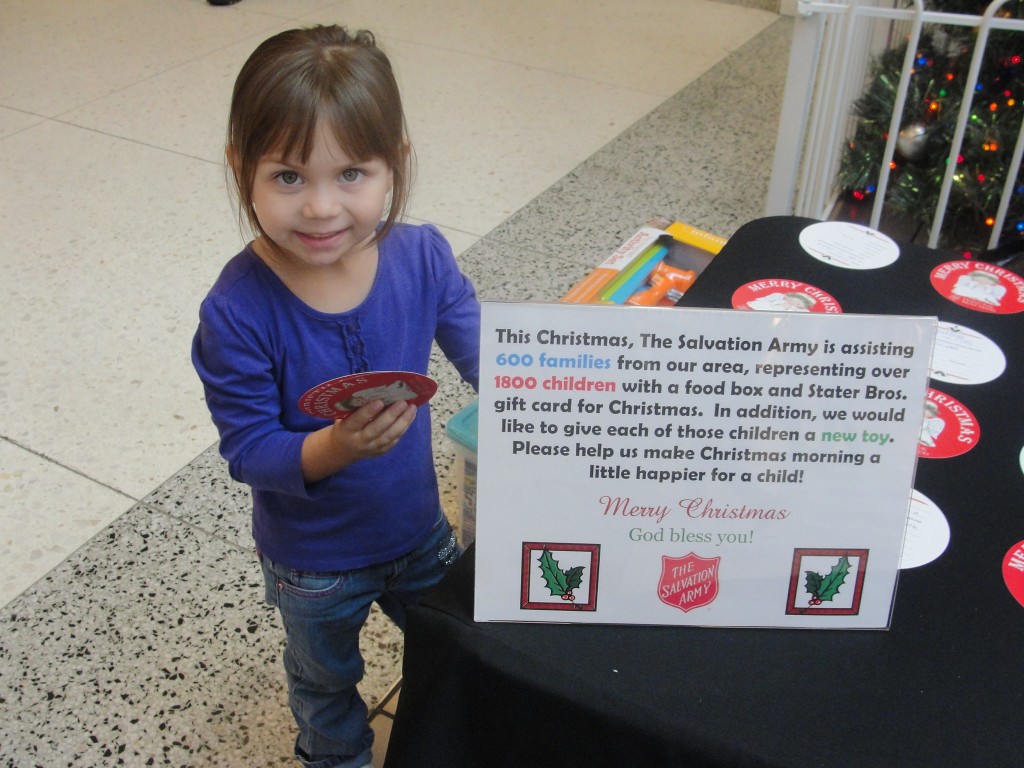  Three year old Allie Chavez is happy to give donations to The Salvation Army’s Giving Tree Program. Photo by Paul Martinez.
