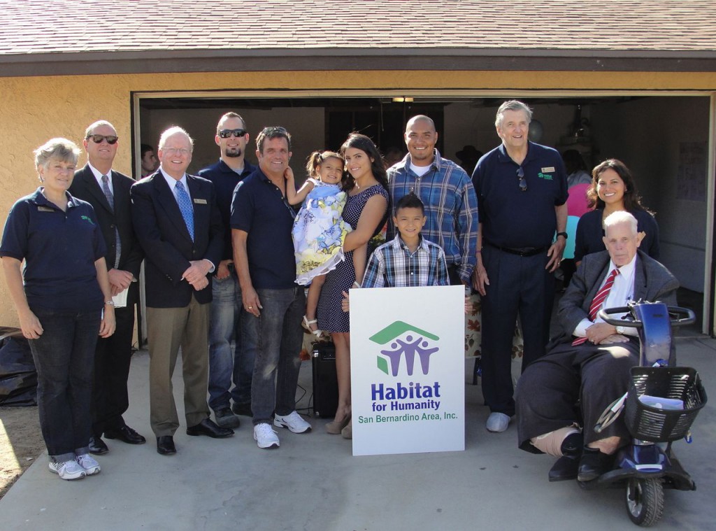 The Espinoza family receives their new home.  Left to right:  Habitat for Humanity Barbara Keough, Secretary; Richard Brown; President; Dennis Baxter, Executive Director; John Biggs, ReStore manager; Tim Garcia, General Contractor; Aubrey Espinoza; Jessica Espinoza, Steven Espinoza, holding the Habitat for Humanity sign Steven Espinoza Jr.; Jack B. Russell, Vice President; Maritza Solis, Office Manager and Volunteer Coordinator; and Hesperia City Council Member Russell "Russ" Blewett.