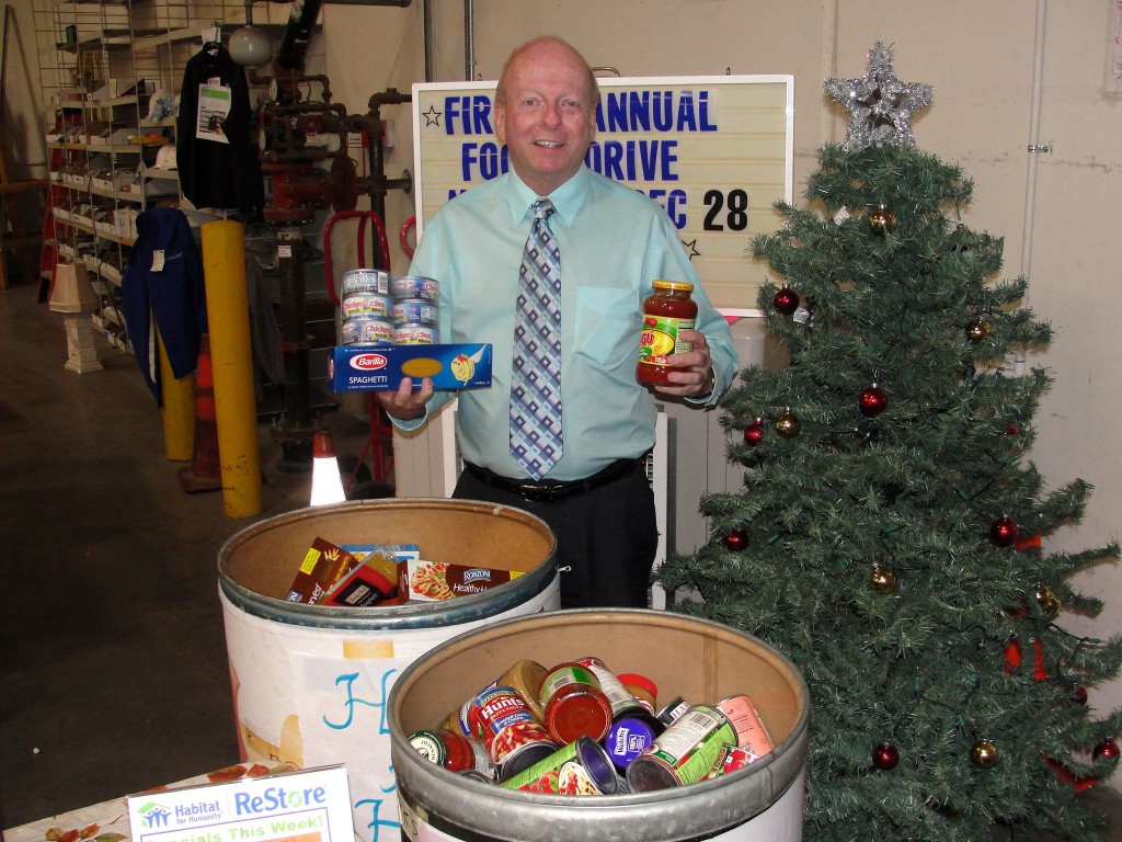 Habitat for Humanity Executive Director Dennis Baxter shows off some the non-perishable food donated for discounts from The Habitat for Humanity ReStore.  Food is donated to the Second Harvest for its holiday Food Drive,